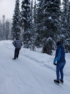 Two people skate along the forest ice track at Apex Ski Resort in the middle of winter in BC.