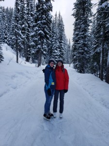 Two people skate along the forest ice track at Apex Ski Resort in the middle of winter in BC.