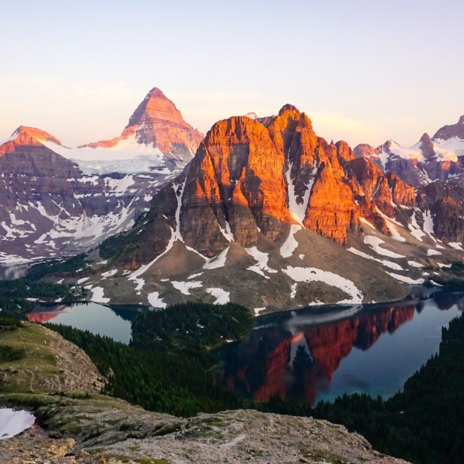 A photo of Mount Assiniboine and Sunburst Mountain and Cerulean Lake at sunset from the Nub in Assiniboine Provincial Park in British Columbia, Canada.