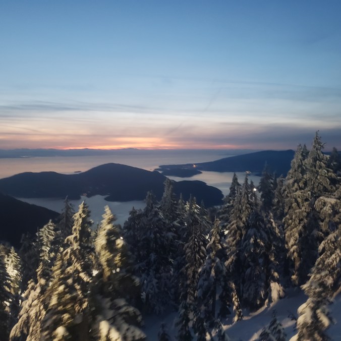 A view of the snowy forest and sunset over Howe Sound and Bowen Island from Sky Chair at Cypress Mountain Ski Resort near Vancouver, British Columbia, Canada.
