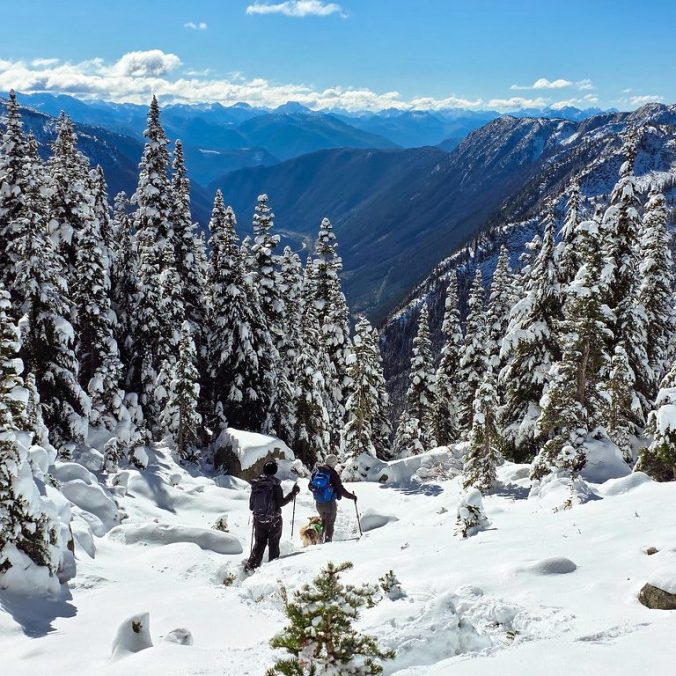 A photo of two hikers in the snow with the forest and trees in the background on Zupok Peak in the Coquihalla Summit Rec Area in BC.
