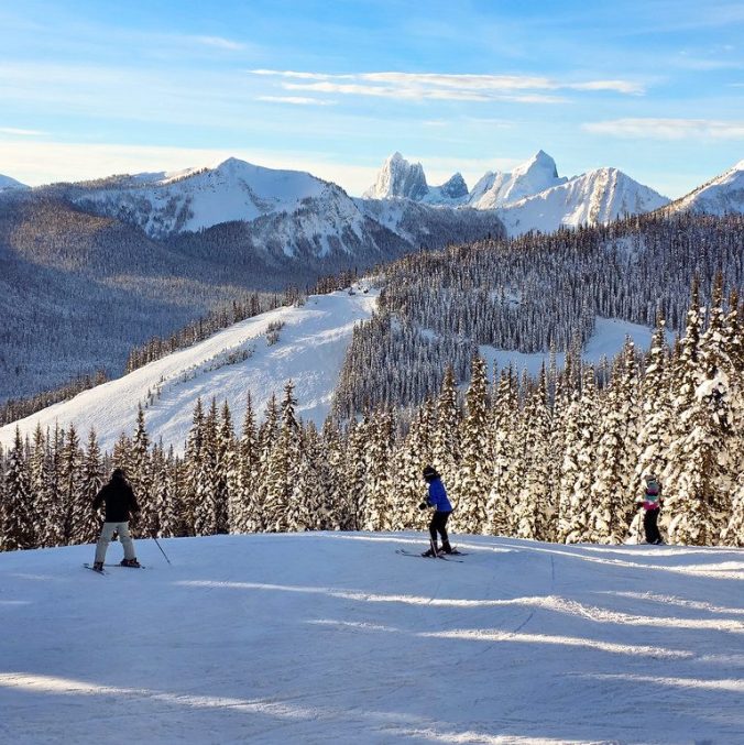 A photo of skiers at Manning Park Ski Resort on a bluebird day with the mountains in the background in British Columbia.