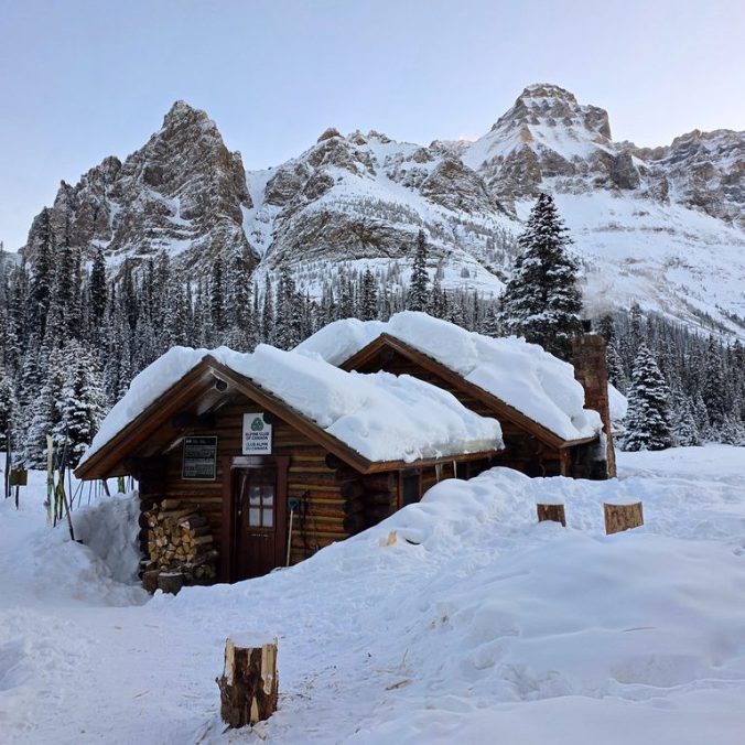 Elizabeth Parker Hut in the winter with the mountains in the background, covered in snow, at Lake O'Hara in Yoho National Park in the Canadian Rockies of BC.